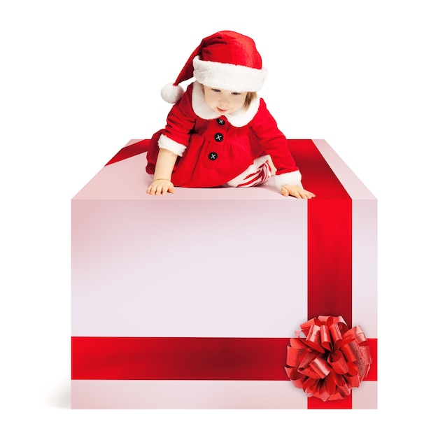 Caja de regalo de Navidad y bebé con gorro de Papá Noel sobre fondo blanco.