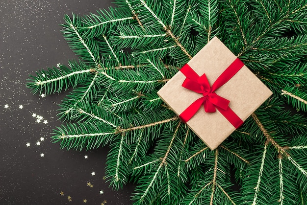 Foto caja de regalo de navidad con cinta roja en ramas de abeto