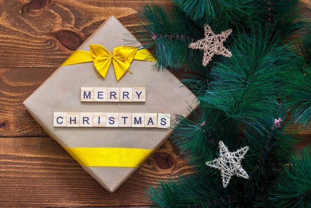 Caja de regalo de Navidad y decoración de rama de árbol en mesa de madera con texto de feliz Navidad.