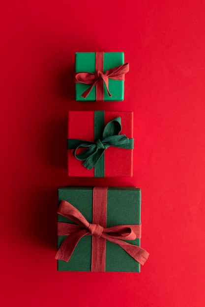 Caja de regalo de navidad festiva atada con una cinta rústica y un lazo sobre un fondo rojo. Vista aérea.