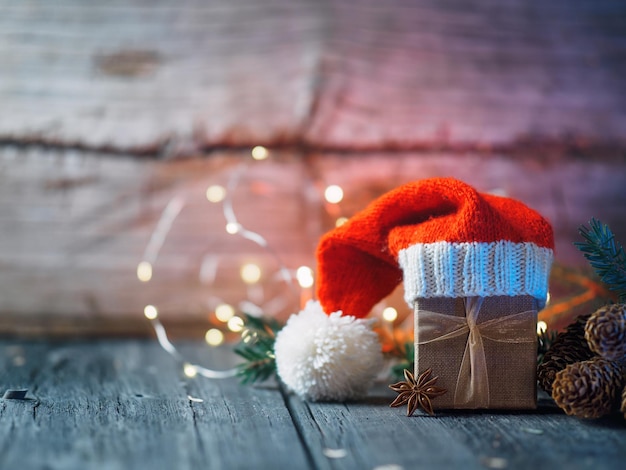 Caja de regalo de Navidad en gorro de Papá Noel sobre fondo antiguo de madera