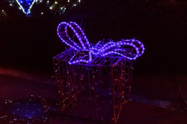 Caja de regalo de Navidad iluminada por la noche. Decoración para las vacaciones de Navidad y año nuevo en un parque de la ciudad.