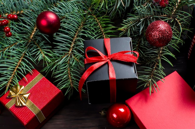 Caja de regalo de navidad negra y roja con cinta roja y ramas de abeto
