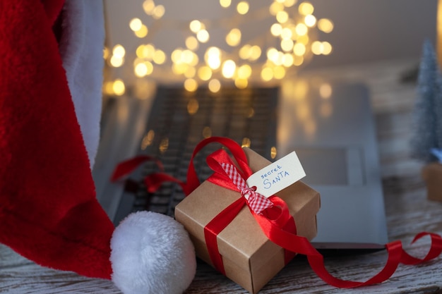 Caja de regalo de Navidad para Papá Noel secreto en el lugar de trabajo con computadora portátil y bokeh Celebración del concepto Papá Noel secreto en la oficina