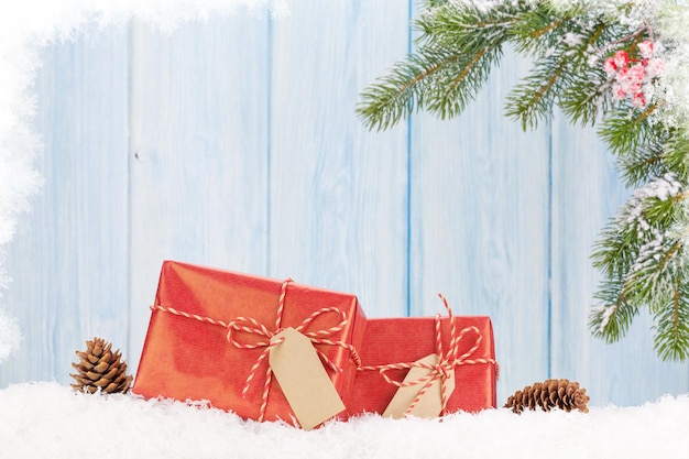 Caja de regalo de navidad y rama de abeto en la nieve