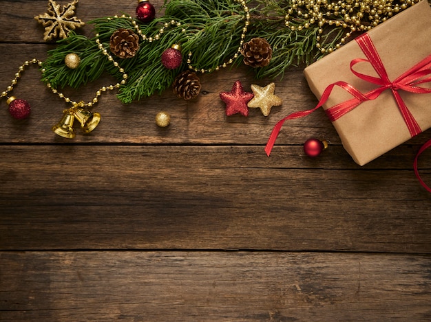 Caja de regalo de Navidad con ramas de abeto y adornos sobre fondo rústico de madera oscura.