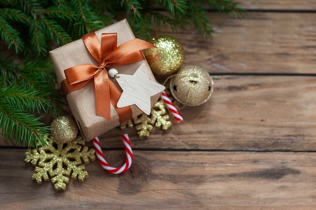 Caja de regalo de Navidad con ramas de abeto y decoración navideña sobre fondo de madera