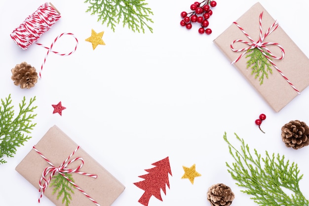 Caja de regalo de Navidad con ramas de abeto, piñas, frutos rojos en mesa de madera blanca bac