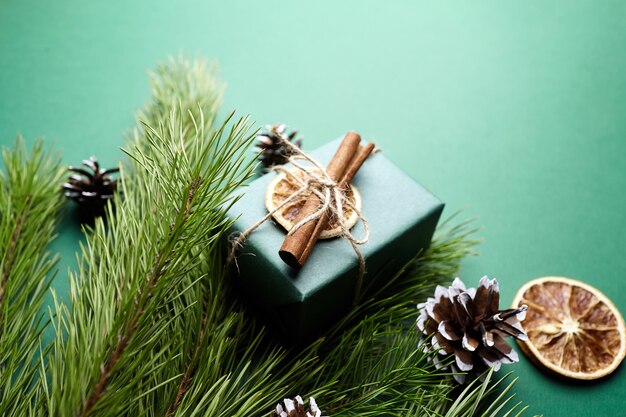 Caja de regalo de Navidad y ramas de pino con decoración sobre fondo verde