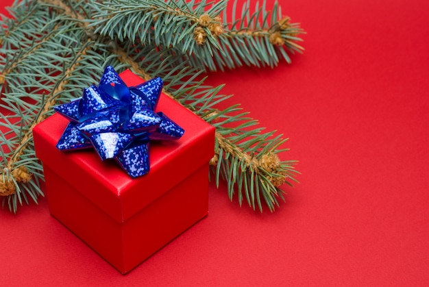 Caja de regalo de Navidad roja con cinta de colores y bolas de Navidad sobre un fondo rojo.