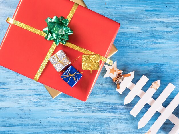 Caja de regalo de Navidad roja grande con cajas más pequeñas sobre fondo azul de madera vintage. Símbolo de celebración.