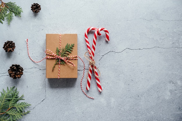 Caja de regalo navideña decorada con una rama de thuja y bastones de caramelo