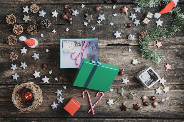 Caja de regalo navideña verde con bastón de caramelo y un pequeño presente colocado en un escritorio de madera rústica