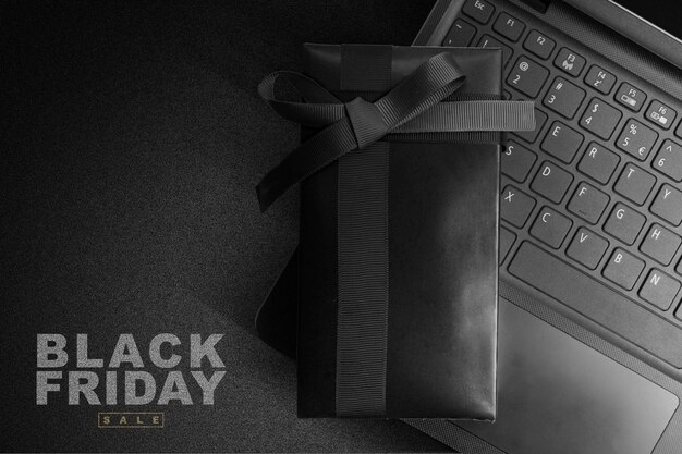 Caja de regalo negra con cinta negra en una laptop con texto de venta de Black Friday