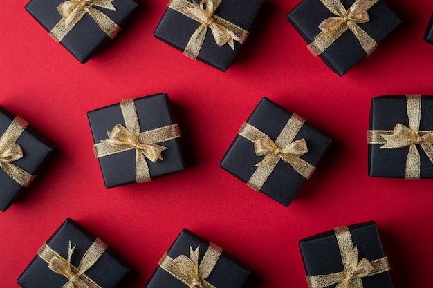 Caja de regalo negra con cintas doradas sobre papel rojo