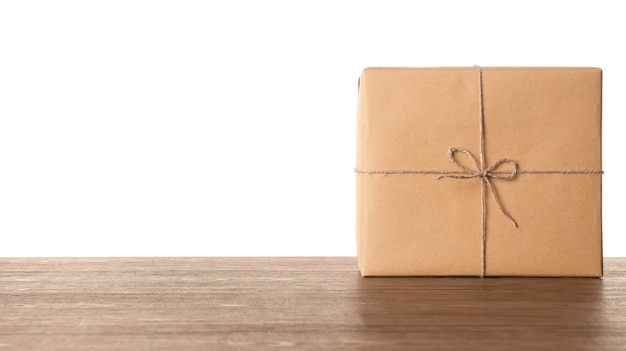 Caja de regalo de paquete en la mesa de madera contra la superficie blanca