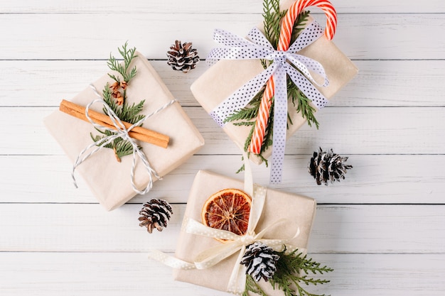 Caja de regalo con piñas y palitos de canela en blanco, decoraciones navideñas vista superior