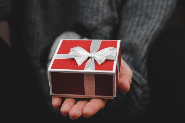 Caja de regalo en primer plano de manos femeninas Mujer sosteniendo una caja de regalo roja