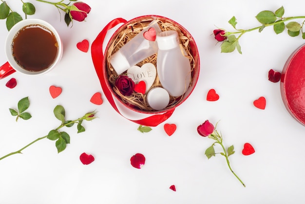 Caja de regalo con productos cosméticos, corazones decorativos, rosas.