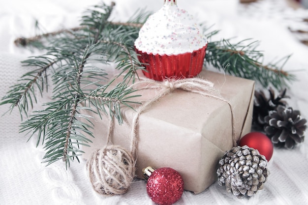 Caja de regalo y rama de árbol de Navidad y adornos sobre fondo blanco.