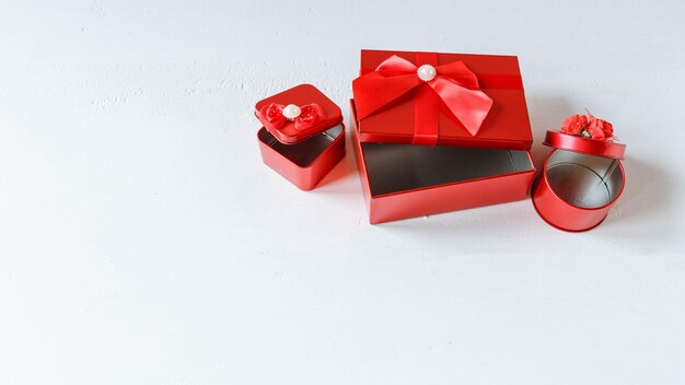 Caja de regalo roja abierta sobre una mesa de madera blanca