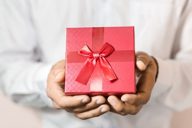 Caja de regalo roja del asimiento del hombre de negocios en manos.