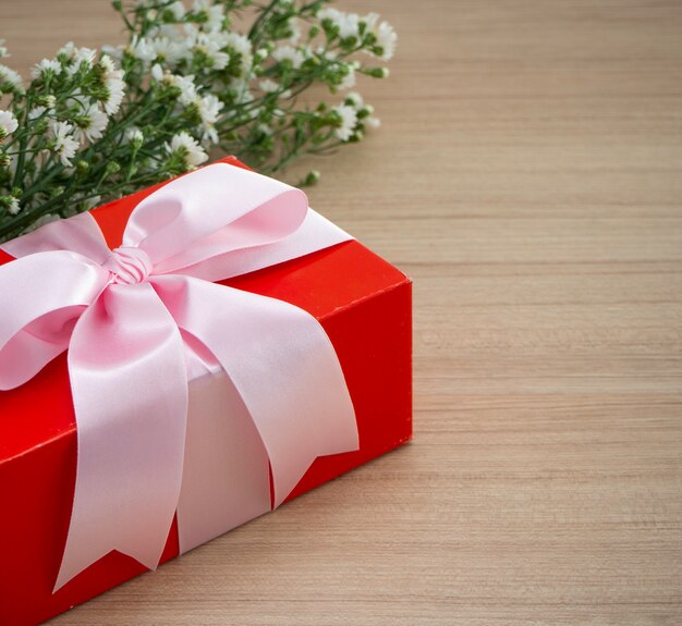 Caja de regalo roja atada con cinta rosa.