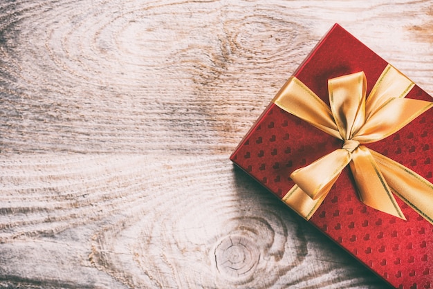 Caja de regalo roja atada con cinta de seda dorada
