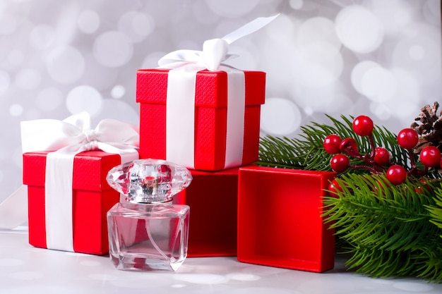 Una caja de regalo roja y una botella de hermoso perfume fragante. Fondo de navidad