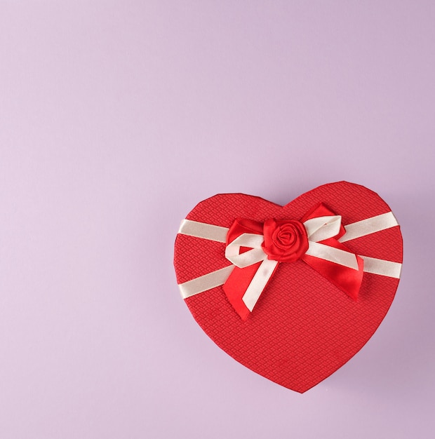 Caja de regalo roja cerrada en forma de corazón con un lazo morado