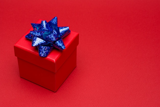 Caja de regalo roja con cinta de colores sobre fondo rojo. Copie el espacio. Espacio para texto.