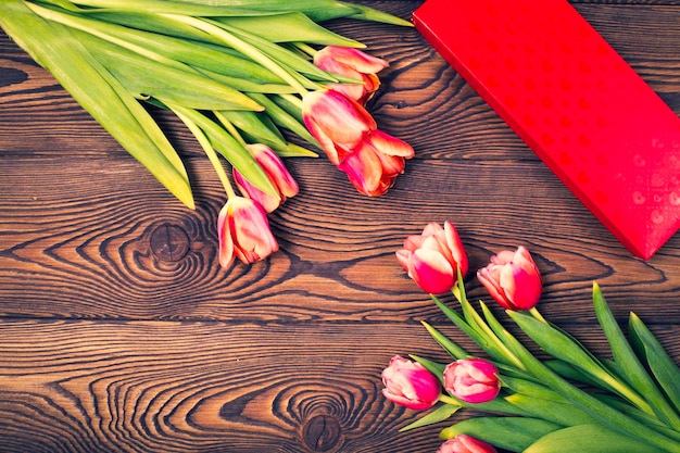 Caja de regalo roja y flores de tulipán en una mesa de madera Lay Flat