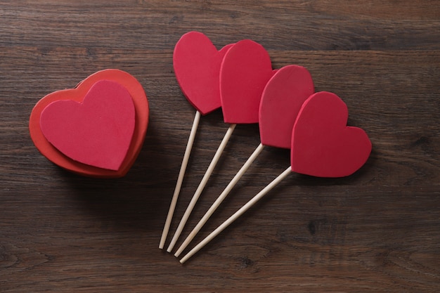 Caja de regalo roja en forma de corazón sobre mesa de madera.