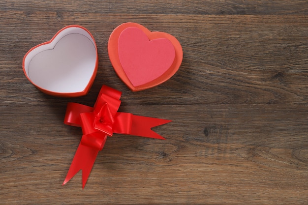 Caja de regalo roja en forma de corazón sobre mesa de madera.