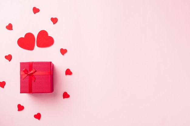 Caja de regalo roja con lazo de cinta y madera en forma de corazones rojos composición tarjeta de felicitación para el amor