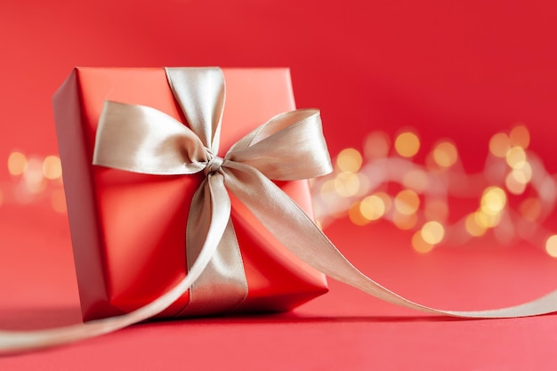 Caja de regalo roja con lazo sobre fondo rojo Concepto de feliz cumpleaños o día de San Valentín