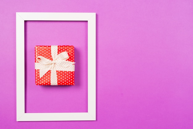 Caja de regalo roja en marco sobre fondo morado. Día de San Valentín