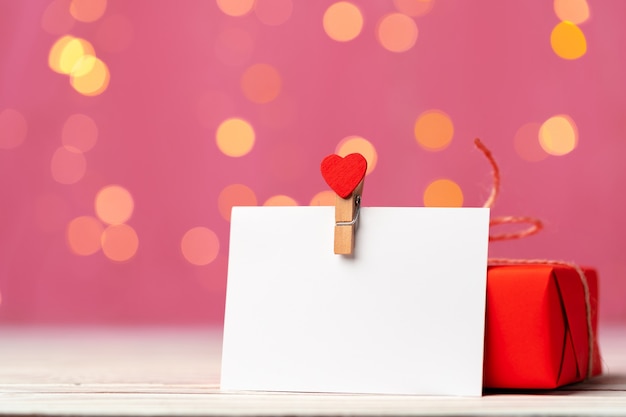 Caja de regalo roja y tarjeta de felicitación sobre fondo rosa de cerca