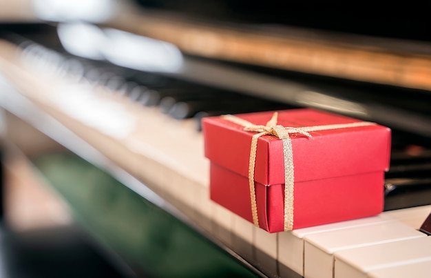 Caja de regalo roja en el teclado de piano para el fondo.