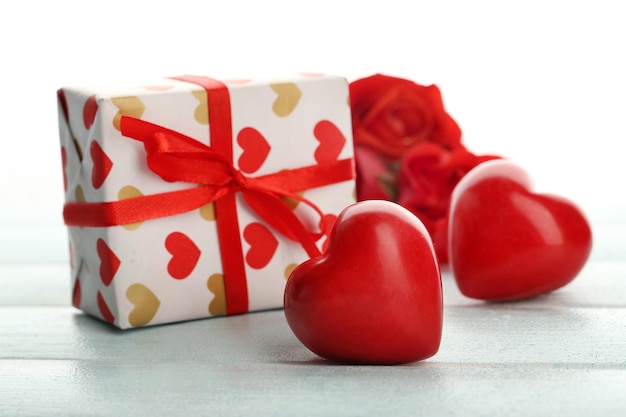 Caja de regalo rosa flores y corazones decorativos en mesa de madera de color sobre fondo claro