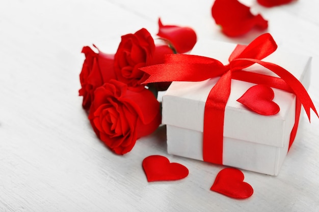 Caja de regalo rosa flores y corazones decorativos sobre fondo de madera clara