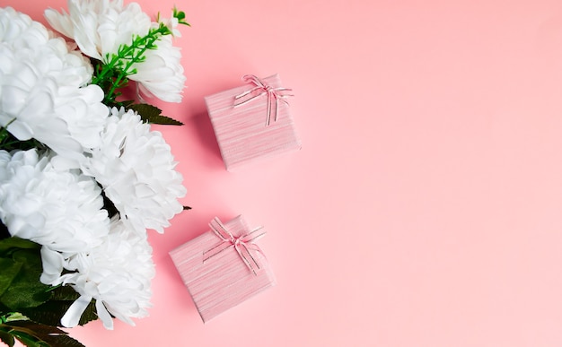 Caja de regalo rosa con lazo de cinta dorada. fondo rosa floral con espacio de copia.