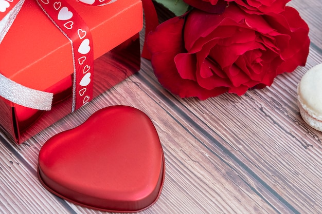 Caja de regalo, rosa roja y una pieza de metal con forma de corazón roja.