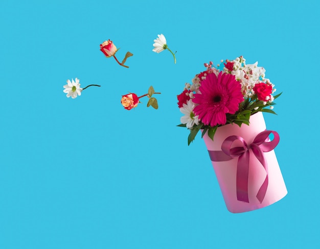 Caja de regalo rosa con varias flores de primavera sobre fondo azul Flores voladoras Idea del Día de la Madre