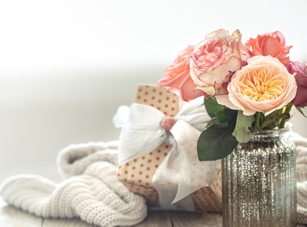 Caja regalo y rosas frescas en florero de cristal para San Valentín o día de la mujer. Concepto de vacaciones.