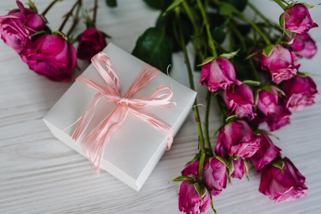 Caja de regalo y rosas rosadas sobre fondo de madera Postal Espacio para mensaje de texto Concepto de flores Tarjeta de felicitación navideña para San Valentín Día de la madre de la mujer Pascua Feliz cumpleaños Vista superior