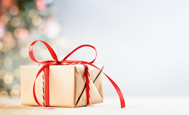 Caja de regalo sobre la mesa en el fondo del árbol de navidad