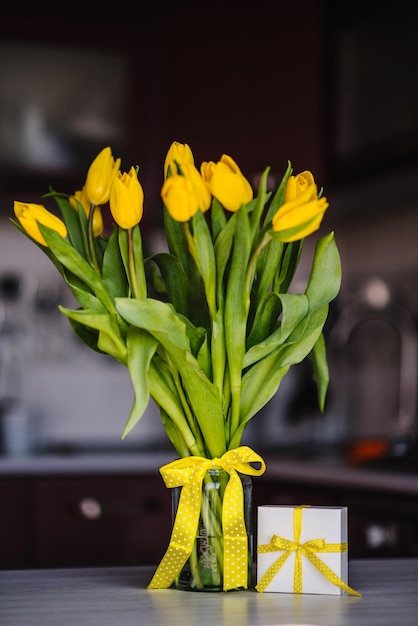 Caja de regalo sorpresa y tulipanes amarillos en la cocina de fondo Espacio para mensaje Tarjeta de felicitación navideña para el Día de la Madre de la Mujer de San Valentín Pascua Feliz Cumpleaños