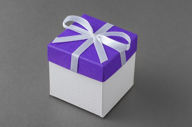 Caja de regalo con tapa azul y lazo sobre fondo gris.