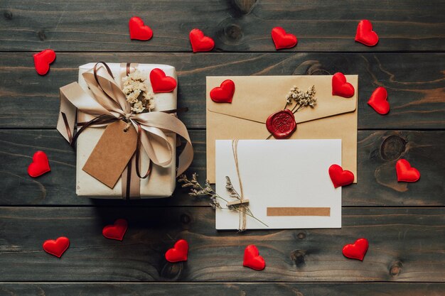 Caja de regalo y tarjeta de felicitación con cinta de lazo y corazones de papel en la mesa de madera para el día de San Valentín. copie el espacio